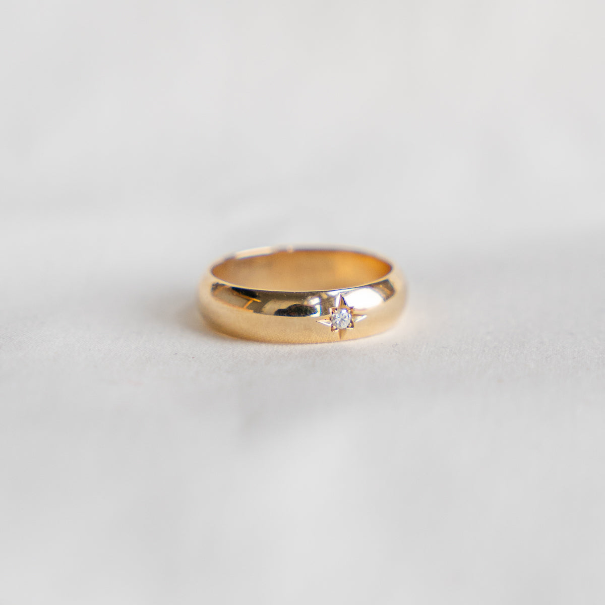 Striking 14K yellow gold 5.5mm wide ring with star set .07ct round brilliant diamond