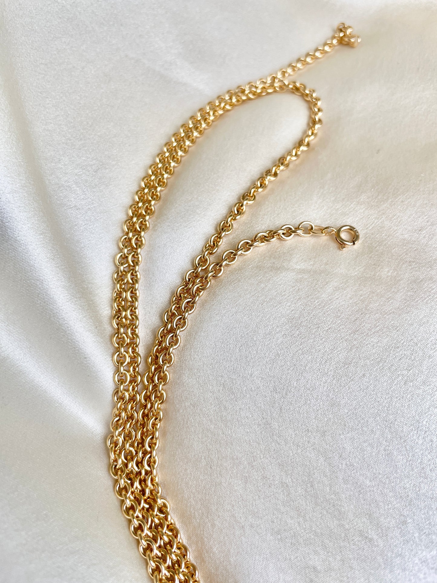 Gold chain necklace on a white fabric background