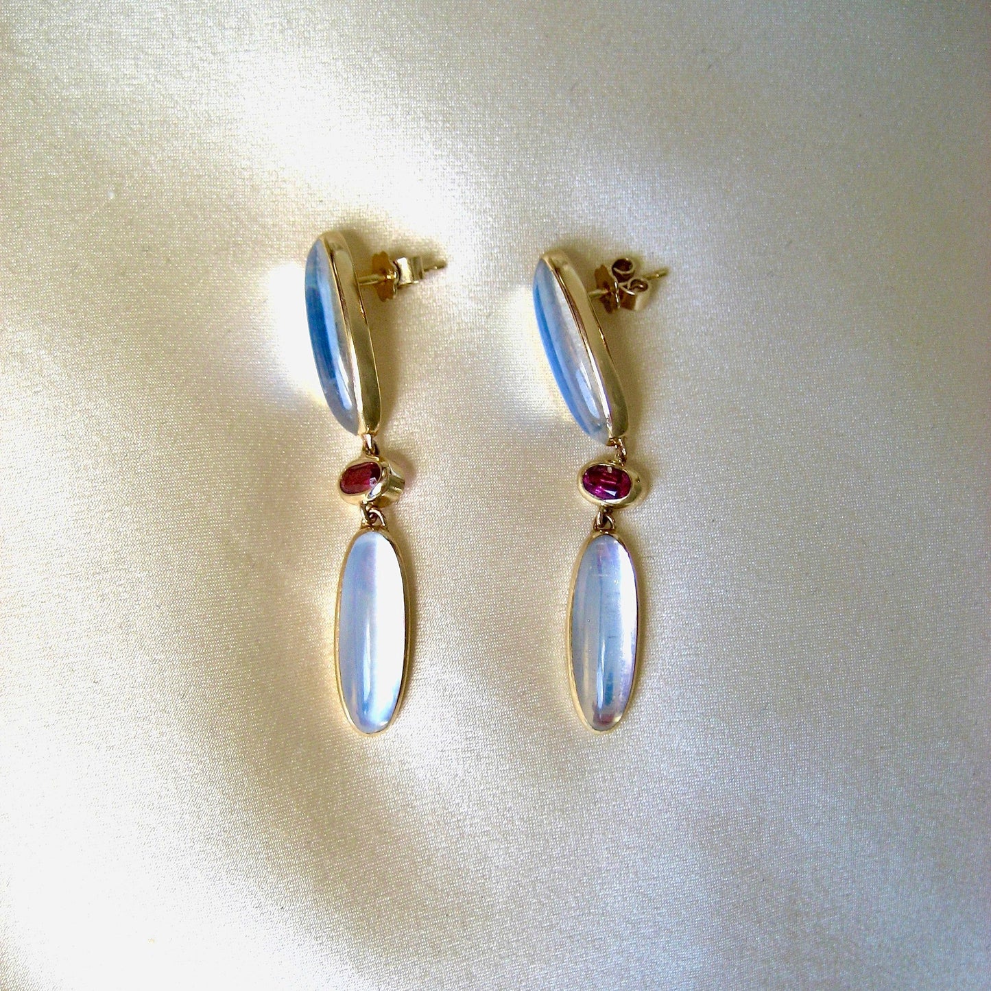 Pair of 14K earrings with moonstone and pink tourmaline gemstone drop earrings on a light background