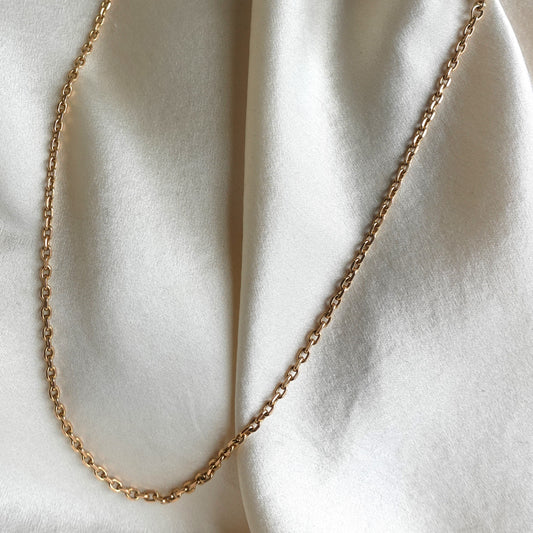 Gold chain necklace on a white fabric background