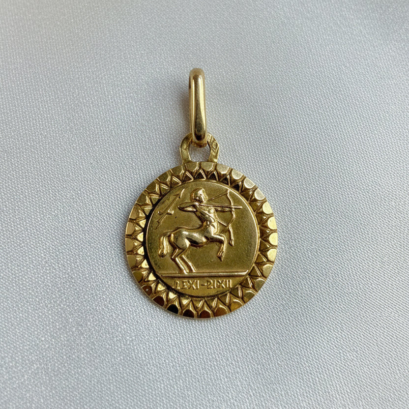 A small round vintage French sagittarius zodiac pendant with a satyr with a bow and arrow and the roman numeric dates for Sagttarius.  A small coin  shaped pendant with a high polished decorative border.