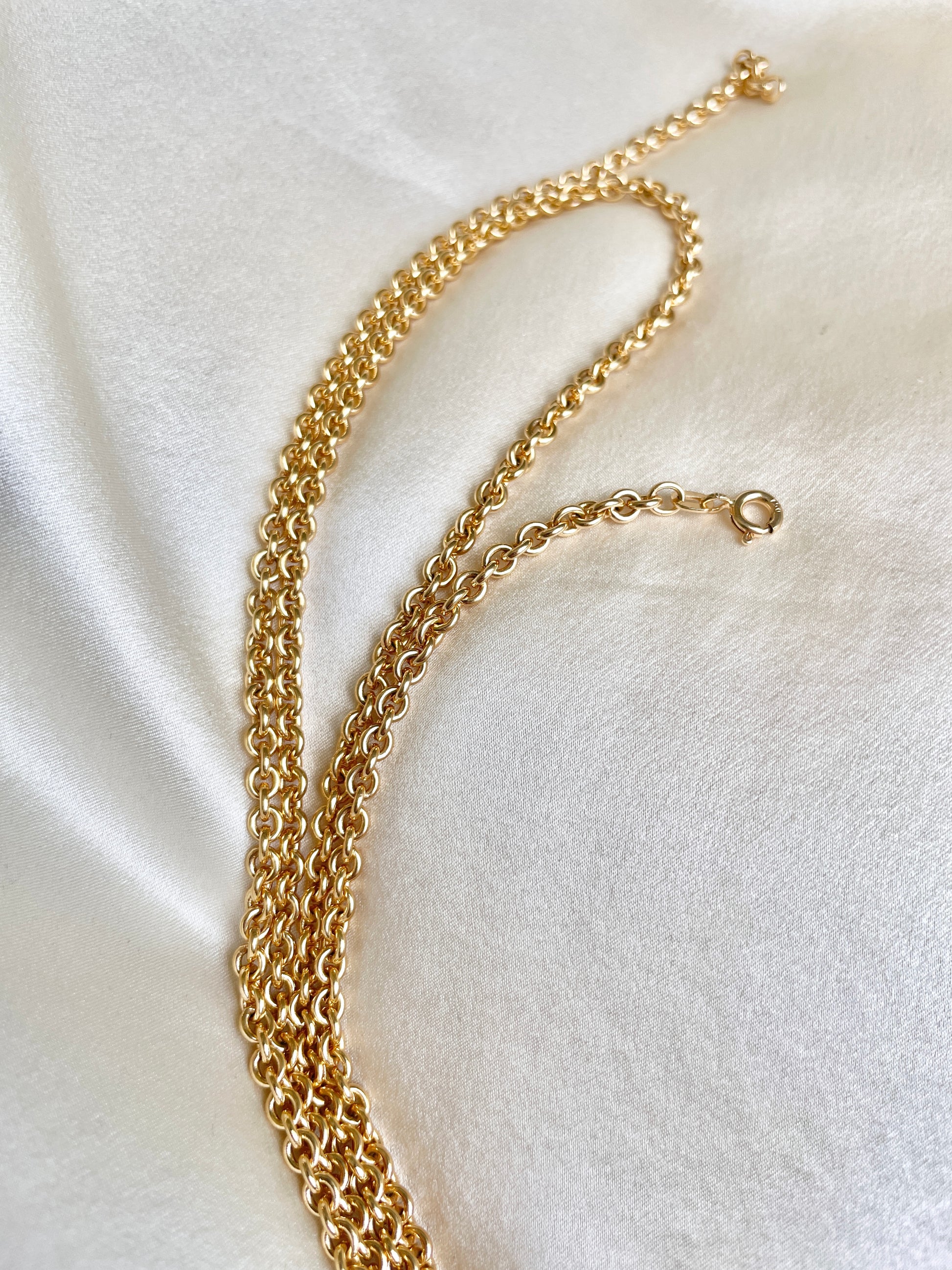 Gold chain necklace on a white fabric background