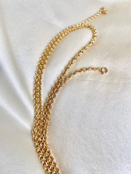 Gold chain necklace on a white fabric background
